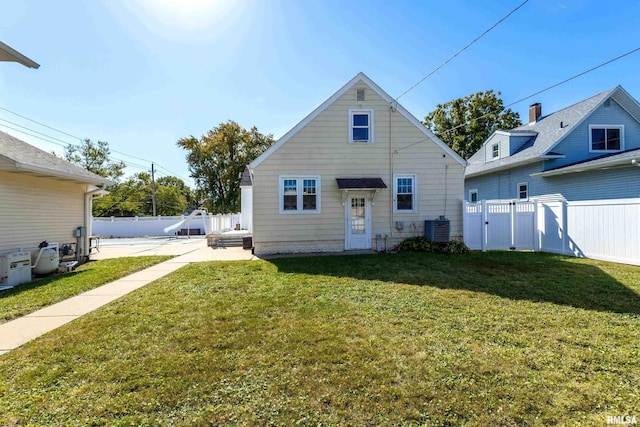 back of property featuring central AC and a yard