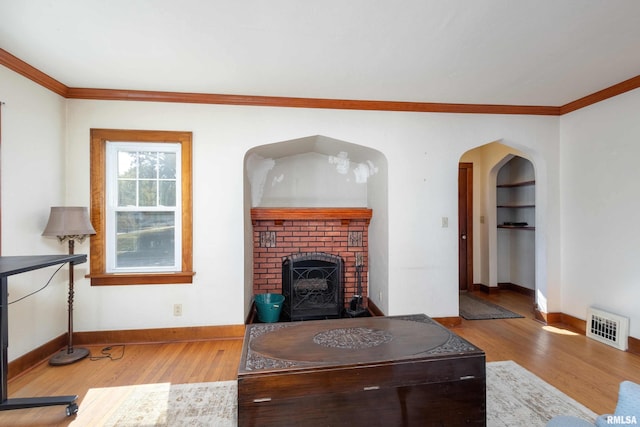 living room with crown molding, built in shelves, and light hardwood / wood-style floors