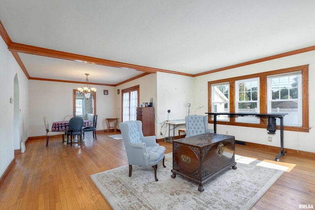 living room with crown molding, a notable chandelier, and light hardwood / wood-style floors