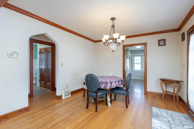 dining space featuring crown molding, a chandelier, and light wood-type flooring