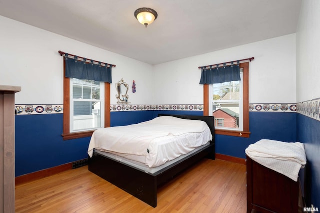 bedroom with multiple windows and hardwood / wood-style floors