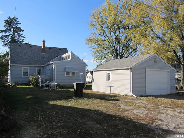 rear view of property featuring a garage and an outbuilding