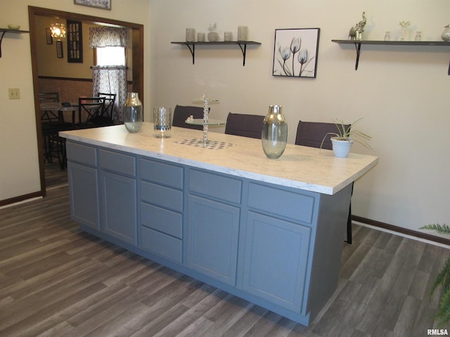 kitchen featuring dark wood-type flooring, a kitchen island, and blue cabinets