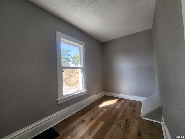 empty room with dark wood-type flooring and a textured ceiling