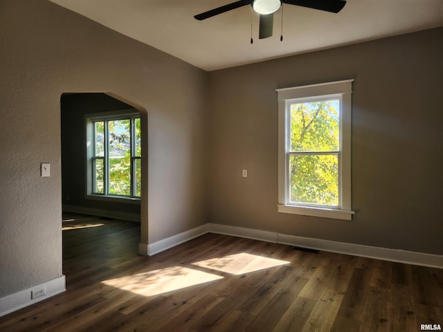 spare room with ceiling fan, a healthy amount of sunlight, and dark hardwood / wood-style floors