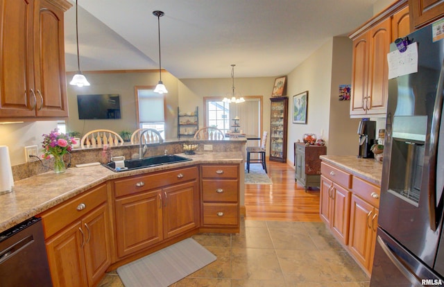 kitchen featuring appliances with stainless steel finishes, sink, light hardwood / wood-style floors, a notable chandelier, and decorative light fixtures