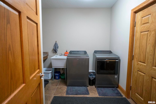 laundry room featuring sink, washing machine and clothes dryer, and dark tile patterned flooring