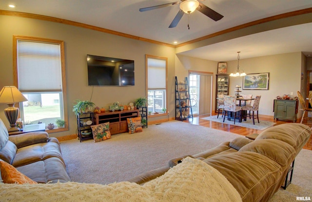 living room with light carpet, crown molding, and ceiling fan with notable chandelier