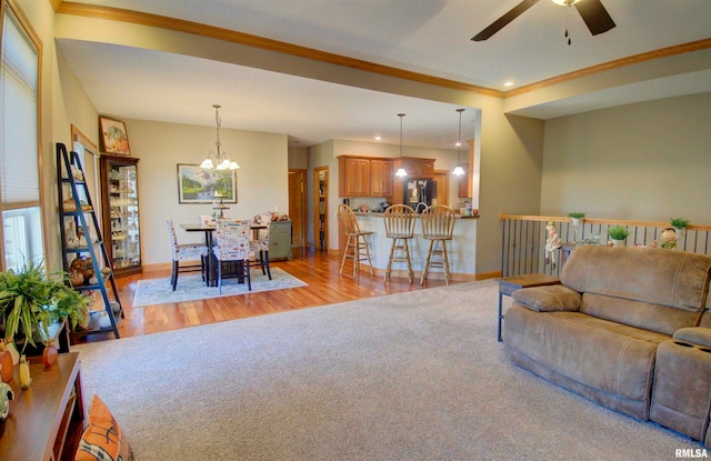 living room featuring ornamental molding, ceiling fan with notable chandelier, and light hardwood / wood-style floors