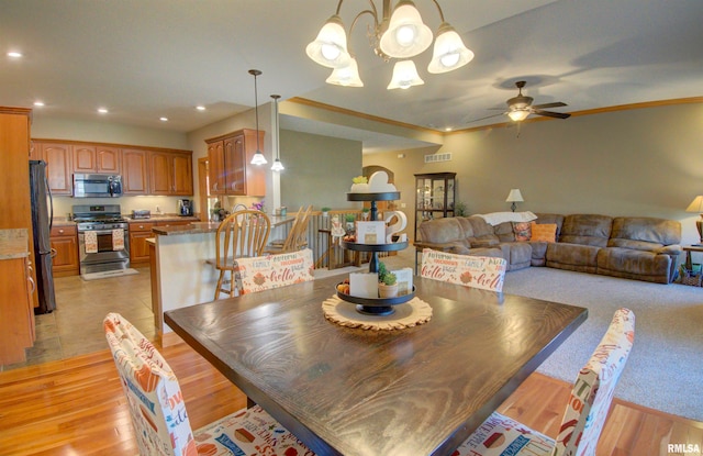 dining area featuring ornamental molding, light hardwood / wood-style flooring, and ceiling fan with notable chandelier