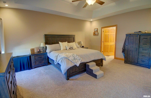 carpeted bedroom with a tray ceiling and ceiling fan