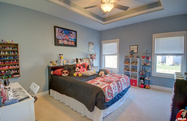 bedroom with a raised ceiling, light carpet, and ceiling fan