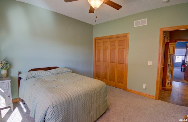 bedroom with a closet, light colored carpet, and ceiling fan