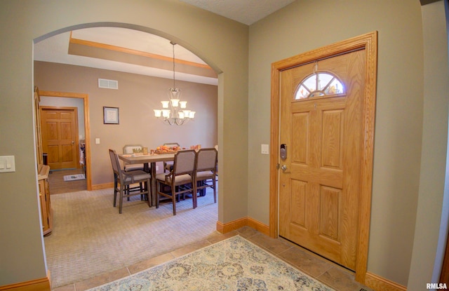 entrance foyer with light tile patterned flooring and an inviting chandelier