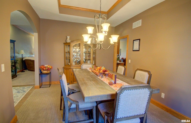 dining space with light carpet, ornamental molding, a chandelier, and a raised ceiling