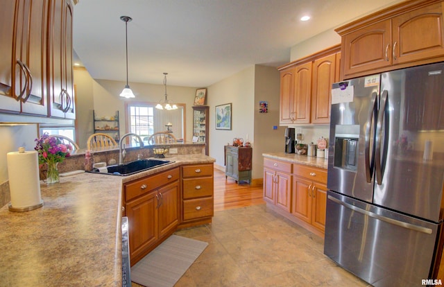 kitchen featuring sink, stainless steel fridge, pendant lighting, and a chandelier