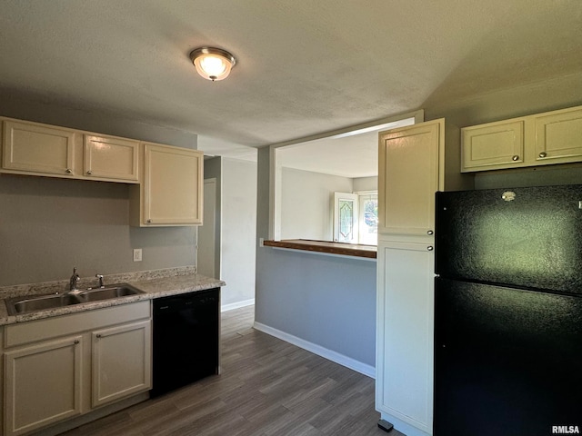 kitchen with hardwood / wood-style flooring, black appliances, sink, and a textured ceiling