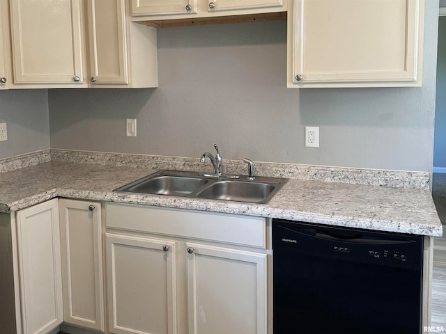 kitchen featuring dishwasher, sink, and light stone counters