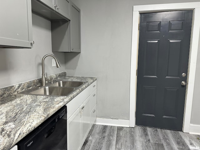 kitchen featuring sink, dishwasher, gray cabinets, dark wood-type flooring, and light stone counters