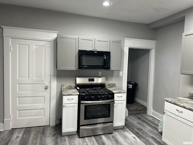 kitchen with white cabinets, hardwood / wood-style flooring, light stone counters, and stainless steel gas range