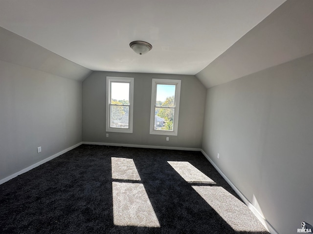 bonus room with lofted ceiling and dark colored carpet