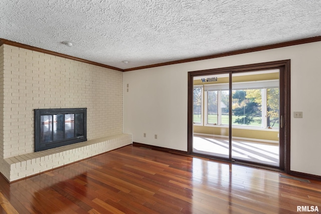 unfurnished living room with a textured ceiling, ornamental molding, a brick fireplace, and hardwood / wood-style floors