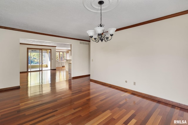 empty room with ornamental molding, a notable chandelier, a textured ceiling, and dark wood-type flooring