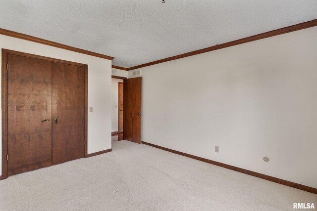 unfurnished bedroom with ornamental molding, a textured ceiling, light colored carpet, and a closet