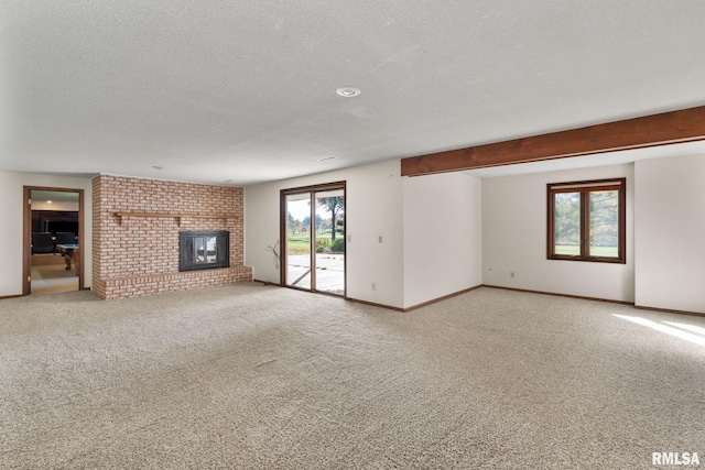 unfurnished living room with carpet floors, a textured ceiling, and a brick fireplace