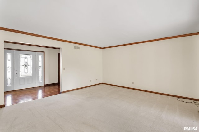 carpeted foyer entrance featuring crown molding