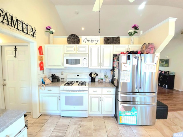 kitchen featuring decorative backsplash, white cabinetry, light wood-type flooring, vaulted ceiling, and white appliances