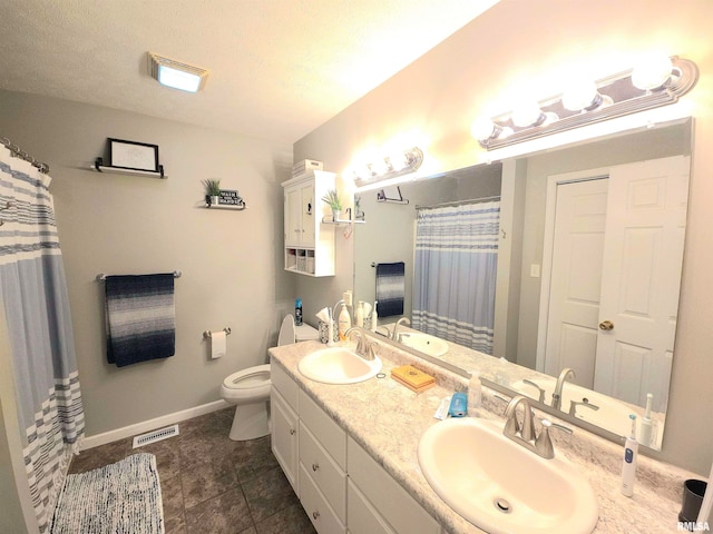 bathroom featuring vanity, a textured ceiling, toilet, and tile patterned floors