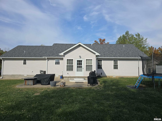 back of house with a patio, a yard, and a trampoline