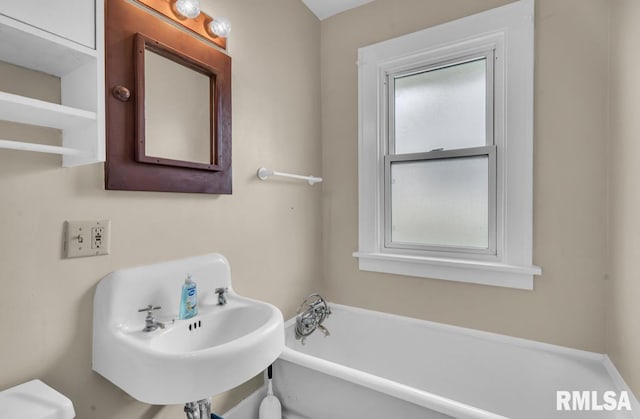 bathroom featuring a washtub, sink, and toilet