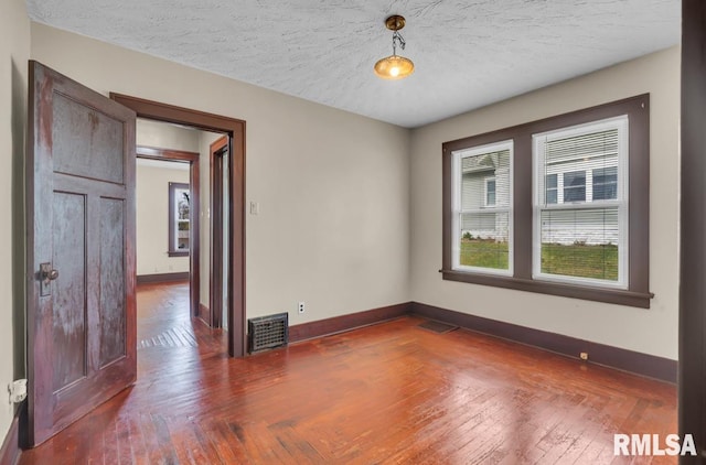 empty room with dark wood-type flooring and a textured ceiling