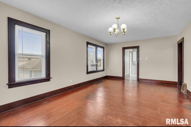 unfurnished room with a textured ceiling, cooling unit, dark hardwood / wood-style flooring, and a notable chandelier