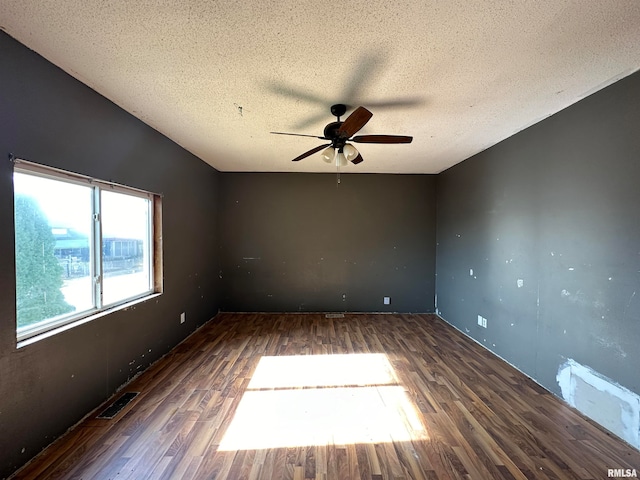 spare room with a textured ceiling, dark wood-type flooring, and ceiling fan