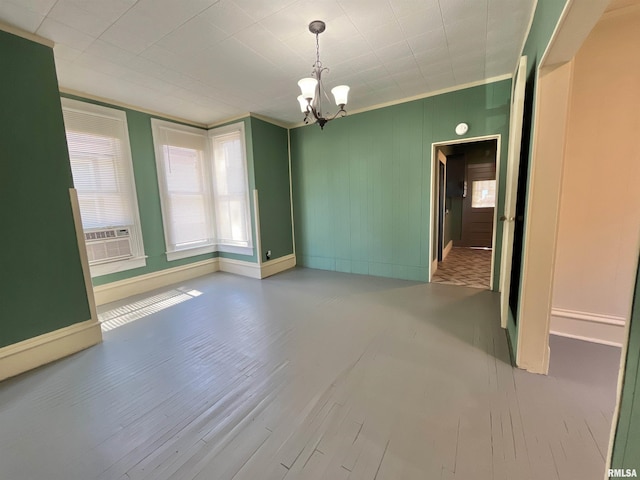 spare room featuring ornamental molding, cooling unit, wood-type flooring, and an inviting chandelier