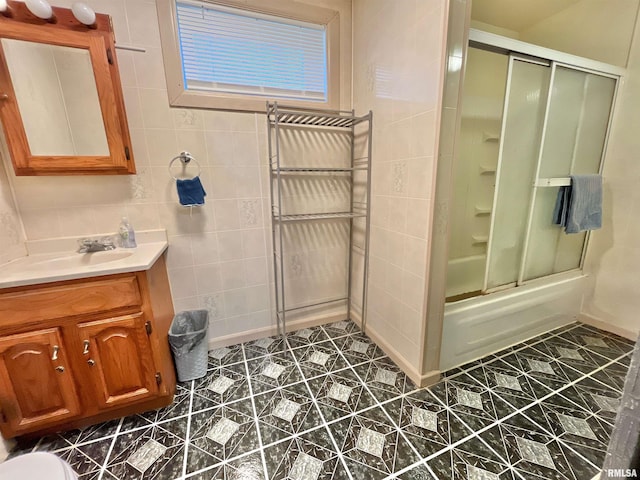 bathroom with shower / bath combination with glass door, vanity, and tile walls