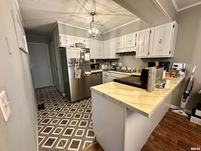 kitchen with kitchen peninsula, white cabinets, appliances with stainless steel finishes, a textured ceiling, and decorative light fixtures