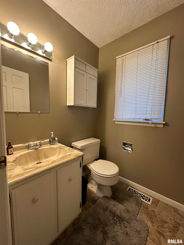 bathroom with vanity, toilet, tile patterned floors, and a textured ceiling