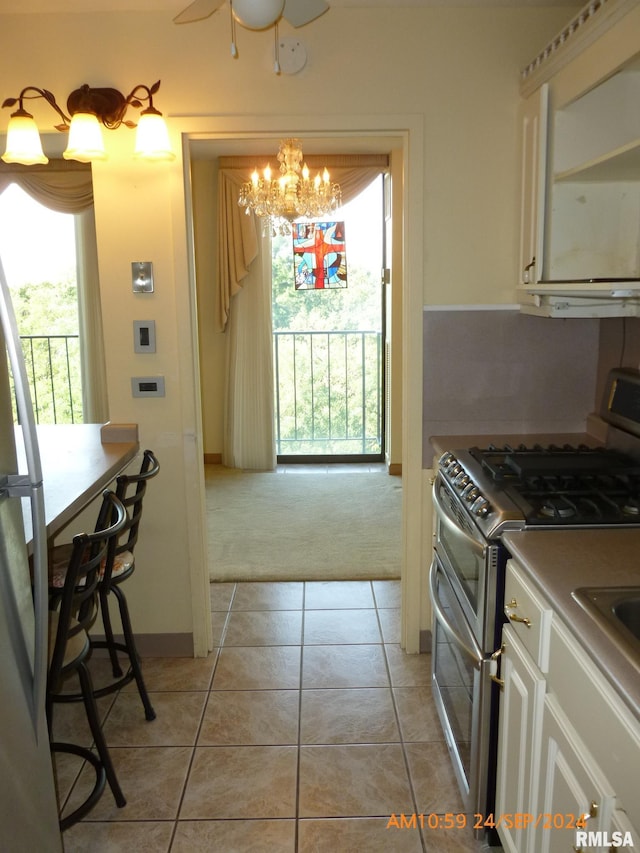 kitchen featuring white cabinets, fridge, light tile patterned floors, and double oven range