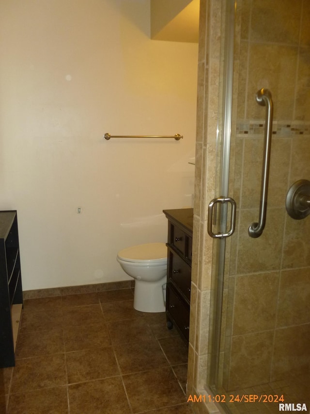 bathroom with vanity, tile patterned flooring, toilet, and a shower with door