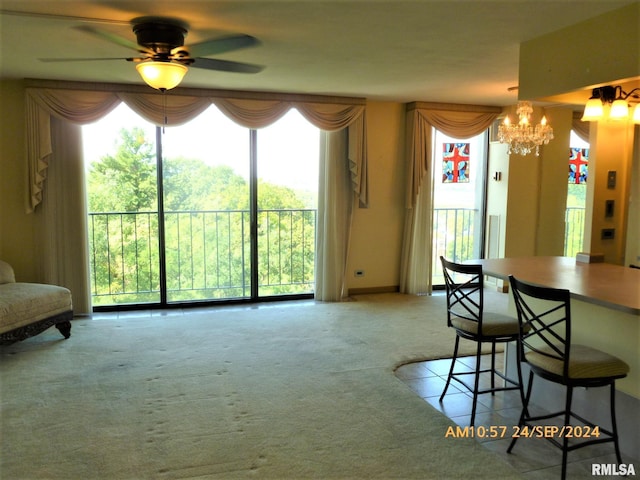 carpeted dining space featuring a wealth of natural light and ceiling fan with notable chandelier