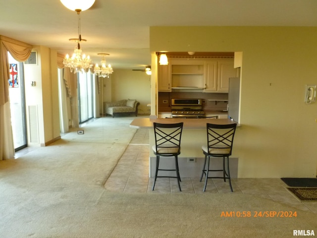 kitchen with a breakfast bar area, light carpet, stainless steel stove, pendant lighting, and ceiling fan with notable chandelier