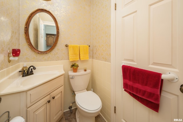 bathroom featuring vanity, toilet, and tile walls