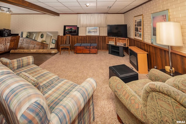 living room featuring wooden walls, carpet, and brick wall