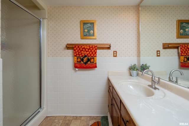 bathroom featuring tile patterned floors, vanity, an enclosed shower, and tile walls