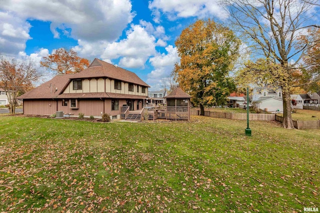 back of property with a sunroom, a deck, a lawn, and central AC