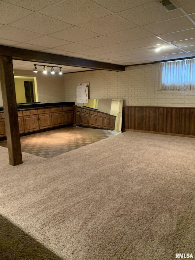 interior space with carpet flooring, track lighting, and brick wall